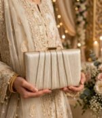 Woman holding ivory party wear clutch bag with embroidered wedding suit