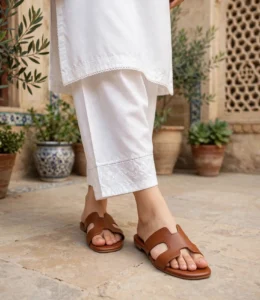Women's flat leather slides in tan paired with a white cotton kurta and trousers