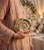 Woman holding golden rose clutch bag with pink embroidered wedding dress