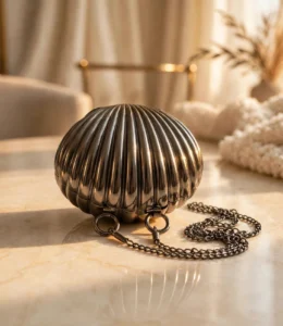 Scalloped metal clutch bag with chain strap on marble table
