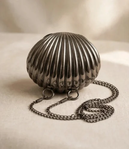 Gunmetal shell clutch bag Pakistan with chain strap on beige fabric