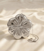 Silver flower shaped clutch bag with chain strap on cream satin