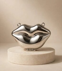 Silver lip clutch bag with side rings for a chain strap on a stone stand